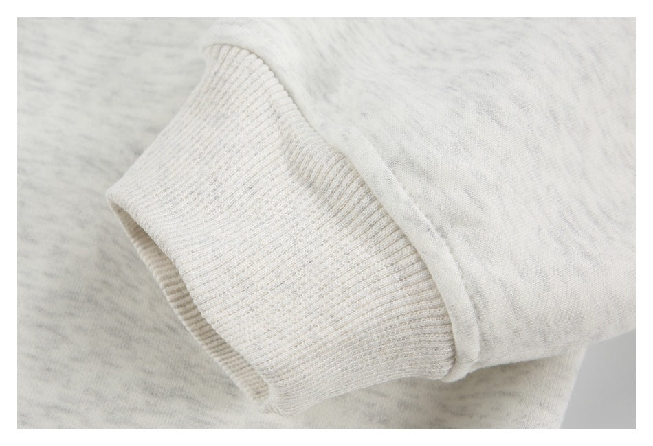 Close-up of a light heather-gray garment sleeve ending in a ribbed cuff.