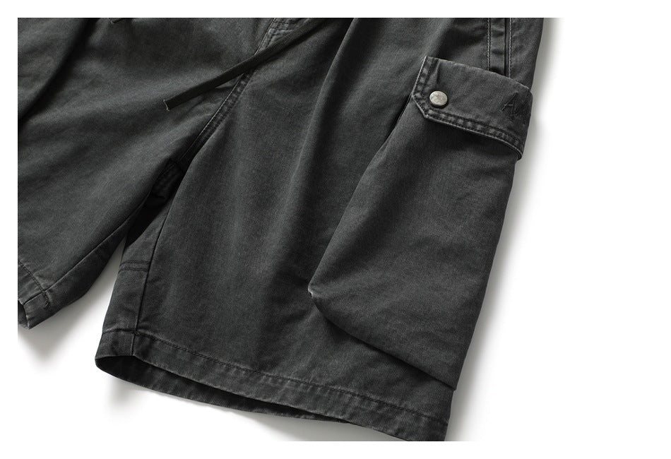 Close-up of charcoal cargo shorts showing a large flap pocket with a snap button.