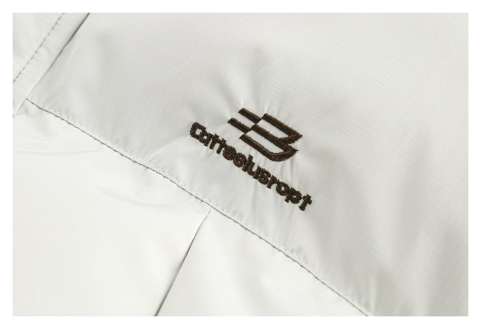 Close-up of dark embroidered lettering and emblem on a white jacket.