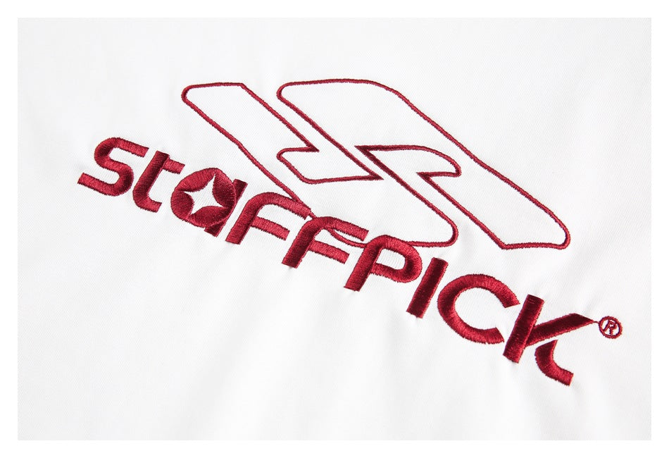 Close-up of red embroidered lettering and an outlined emblem on white fabric.
