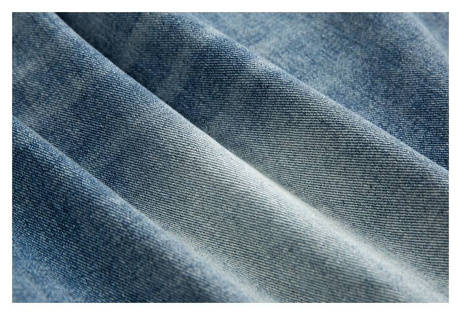 Close-up of the blue denim fabric showing its diagonal weave and varied wash.