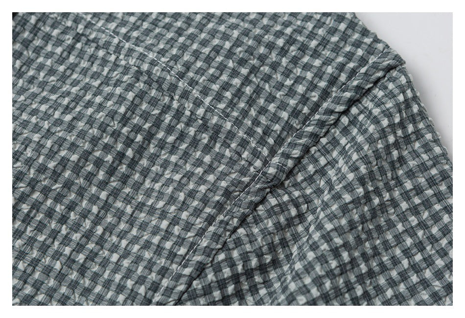 Close-up of gray, black, and white checkered fabric with a diagonal stitched seam.