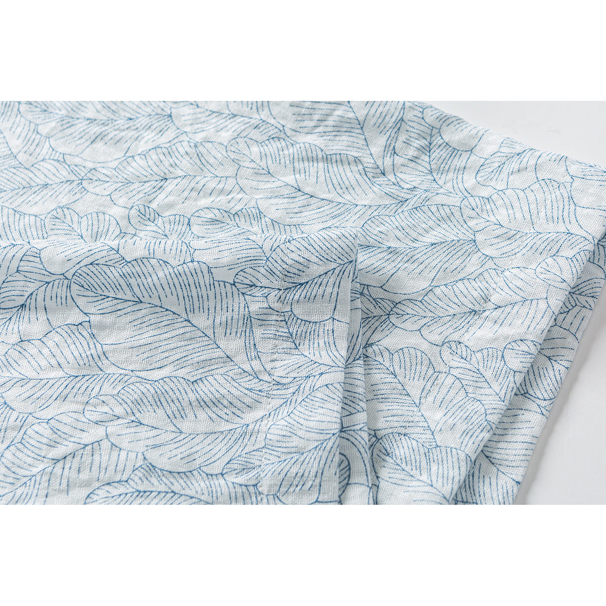 Close-up of pale blue leaf outlines on white shirt fabric, showing the repeating botanical pattern.