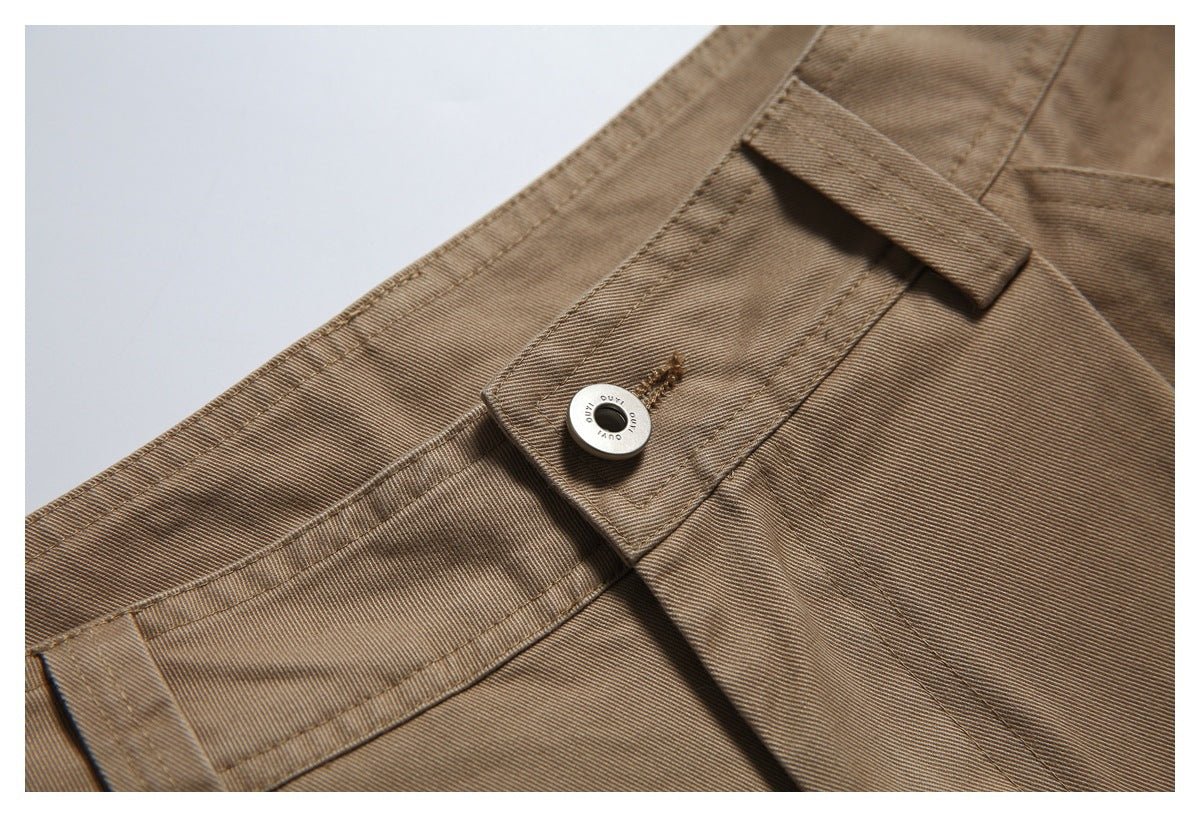 Close-up of tan trousers showing the waistband, belt loop, and metal button.