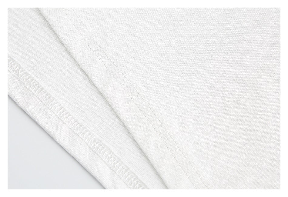 Close-up of white garment fabric showing a seam and overlock stitching.