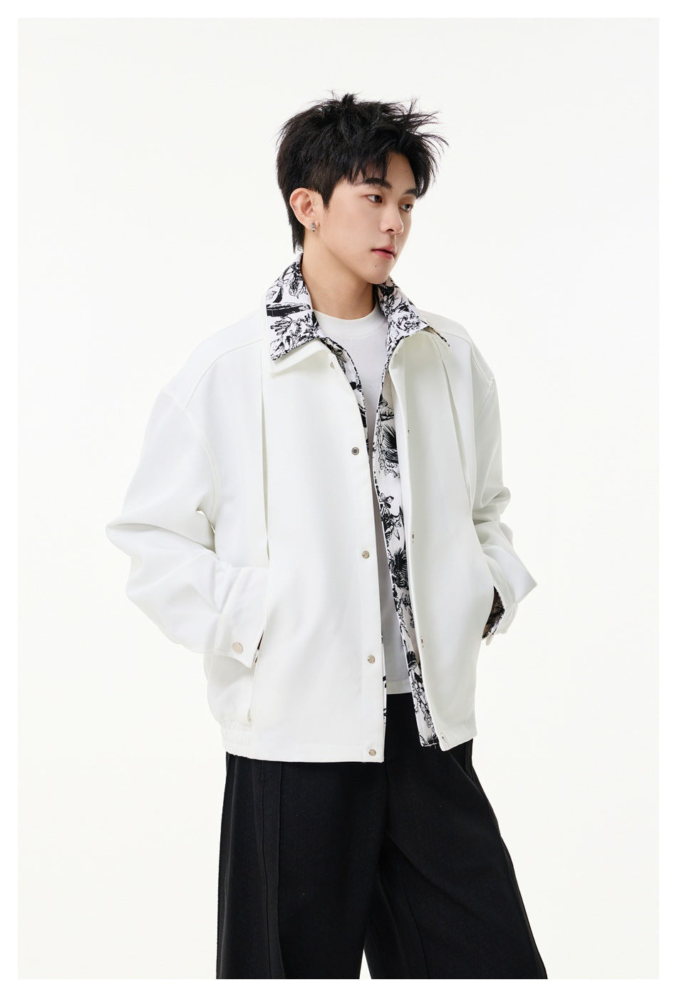 Model wearing a white snap-front jacket with black-and-white botanical print collar and trim.