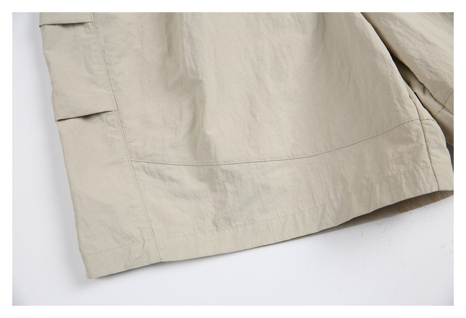 Close-up of the lower leg and hem of light beige pants with a side cargo pocket flap.