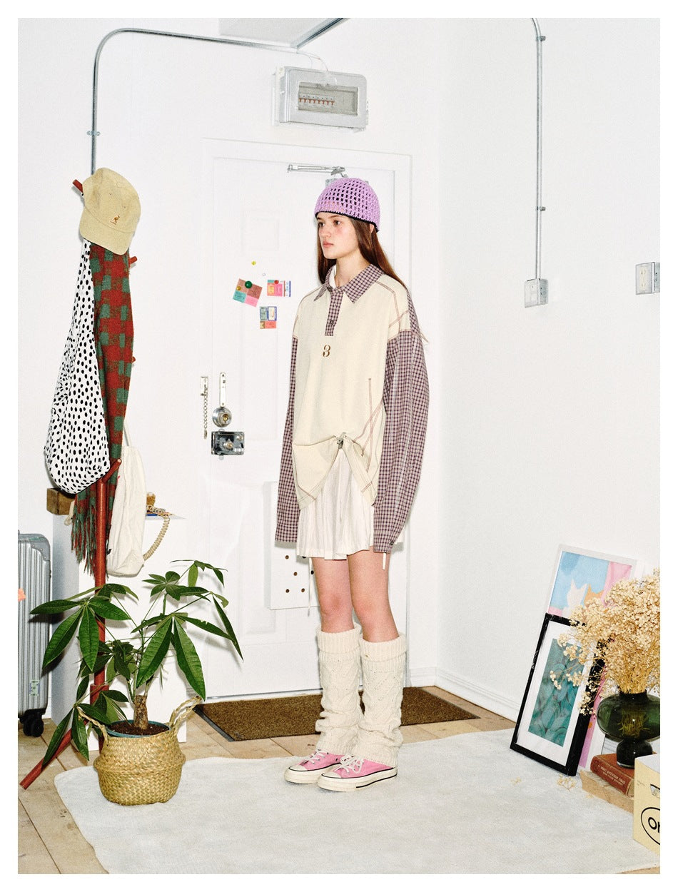 Side-angle view of model in the apricot top with plaid sleeves, front hem knotted, with white skirt and pink sneakers