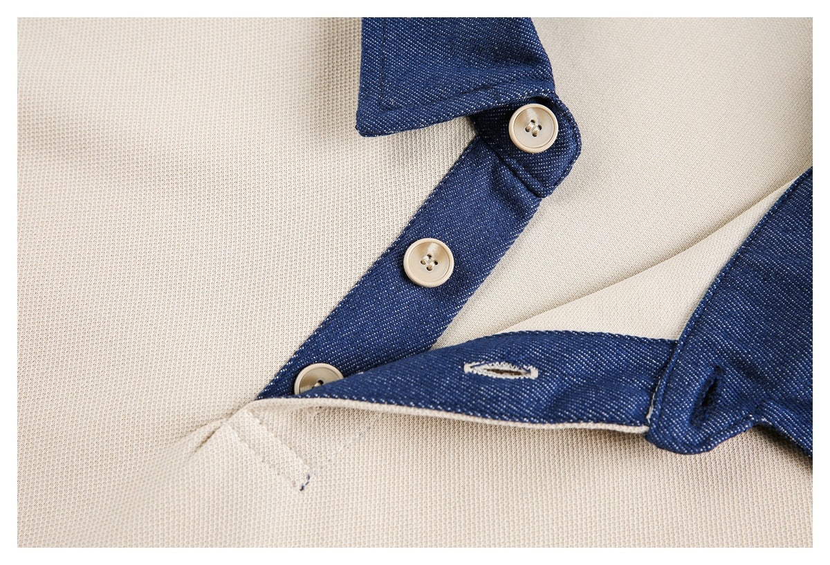 Close-up of a cream-beige garment with a navy contrast placket, light buttons, and a small buttonhole.