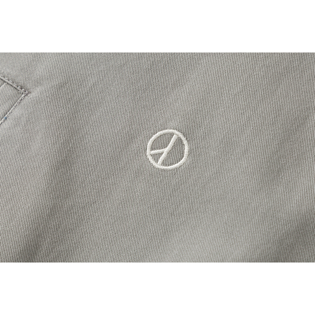 Close-up of a small white embroidered emblem on gray jacket fabric.
