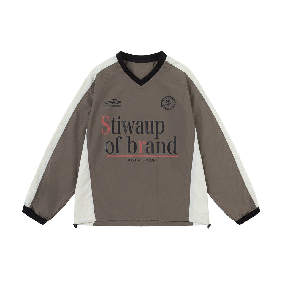 Light brown V-neck long-sleeve pullover with cream raglan panels, black trim and chest graphic print, flat front view
