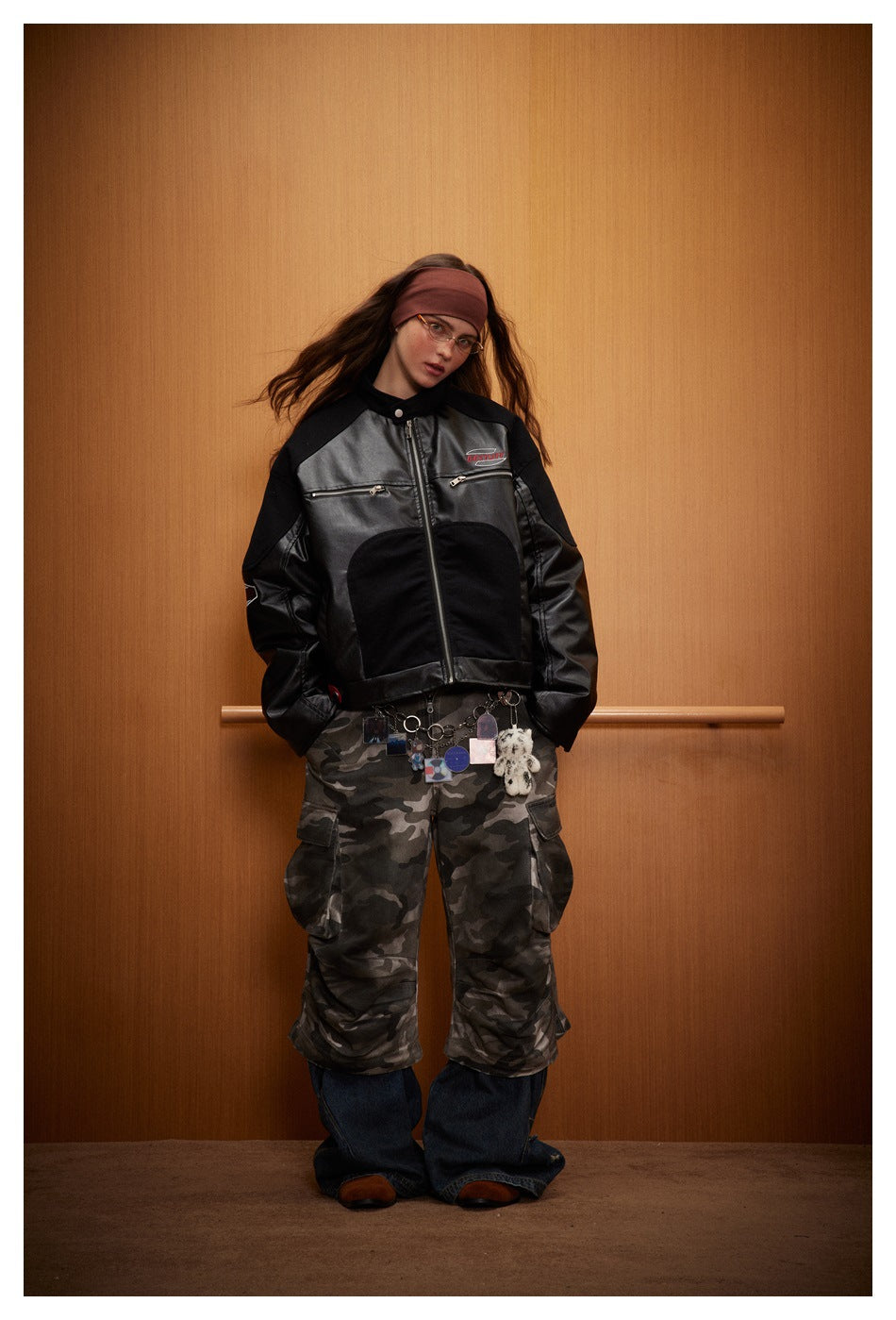 Full-length front view of a model in a black color-block zip jacket and camouflage cargo pants.