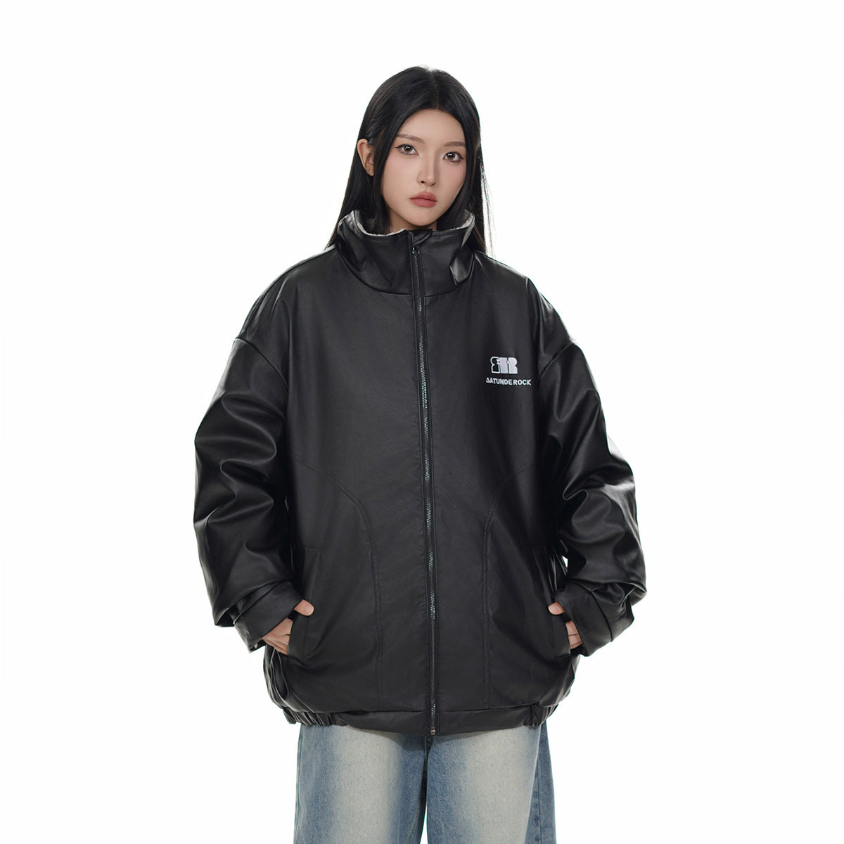 Model wearing an oversized black zip-front jacket with a tall collar and curved front pockets.
