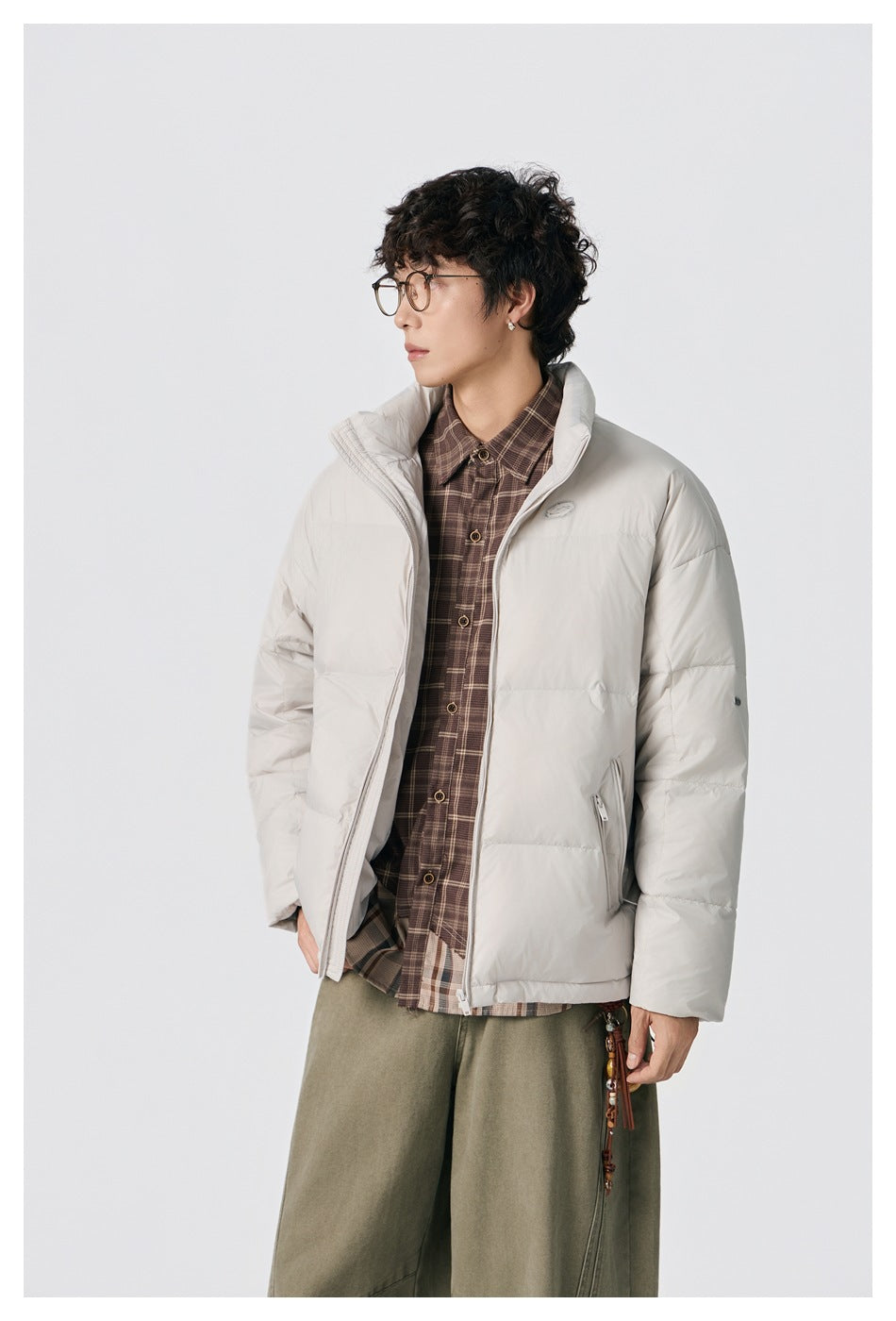 Closer view of a model wearing an open off-white puffer jacket over a brown plaid shirt.