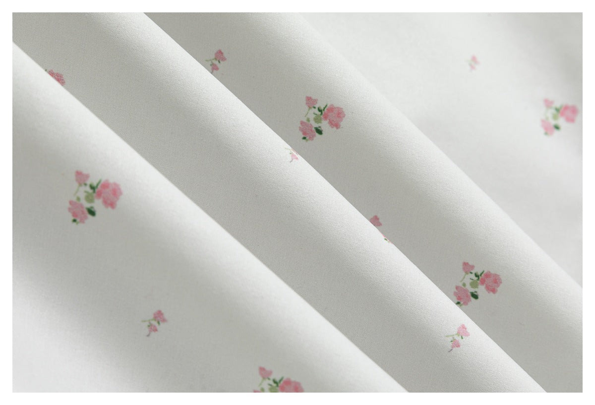 Close-up of softly folded white fabric scattered with small pink floral clusters.