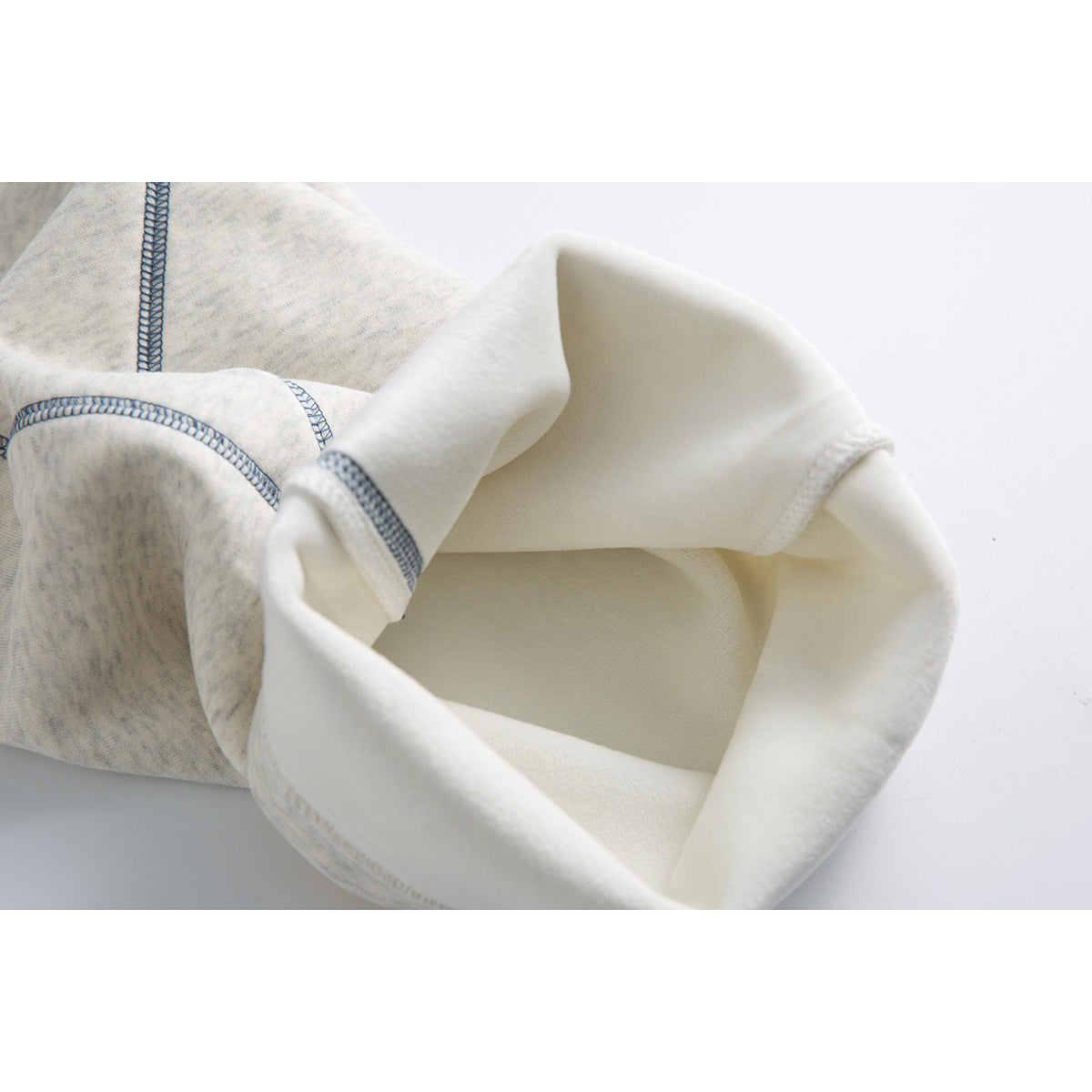 Close-up of a turned-up pant leg showing the light interior and contrasting blue-gray overlock stitching.