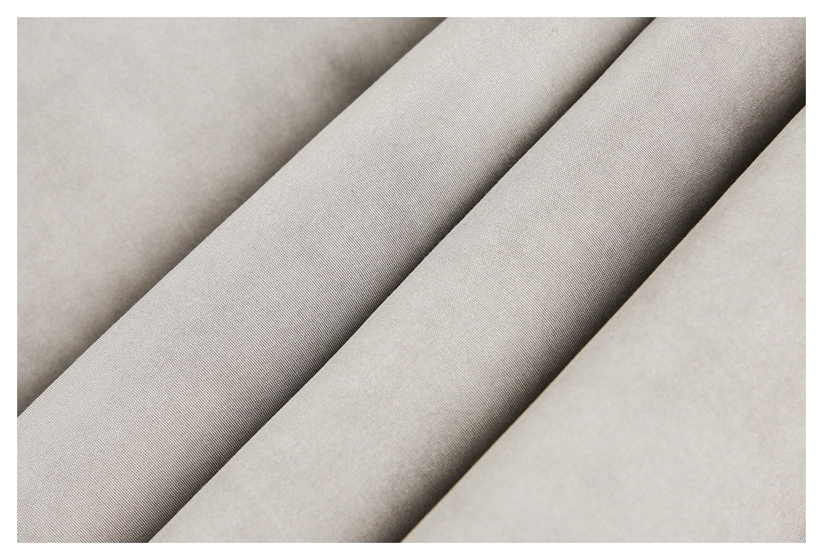 Close-up of taupe-gray jacket fabric folded into diagonal ridges.