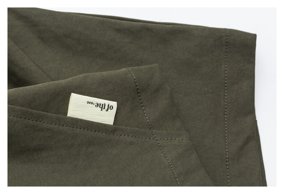 Close-up of an olive trouser pocket with a small sewn English-text label.