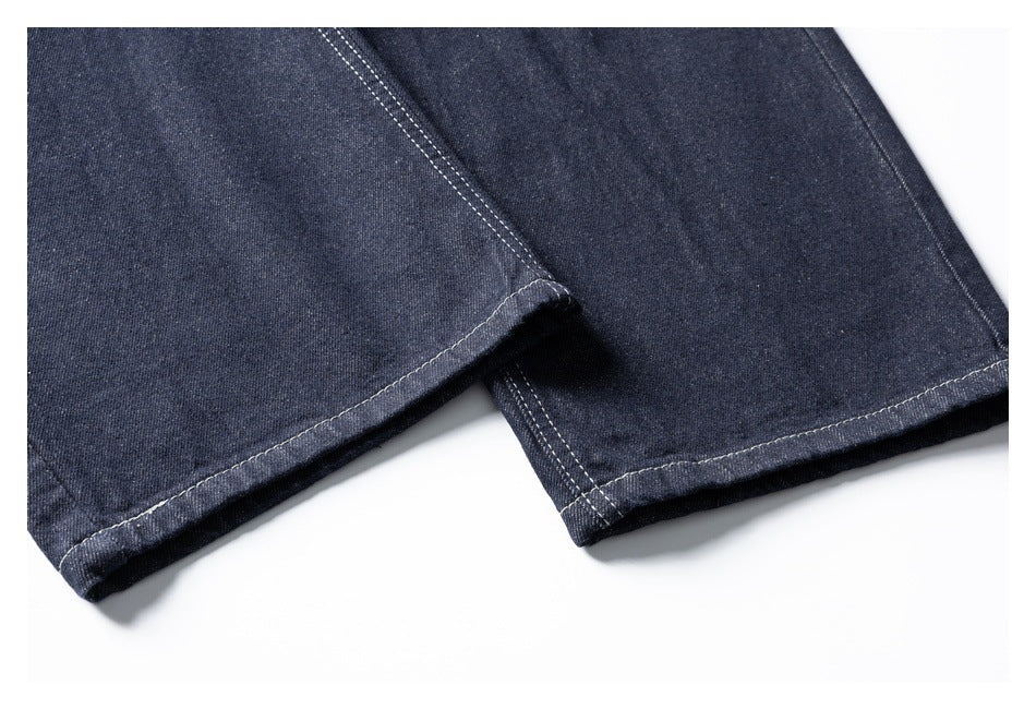 Close-up of dark indigo jeans leg hems with visible double stitching.
