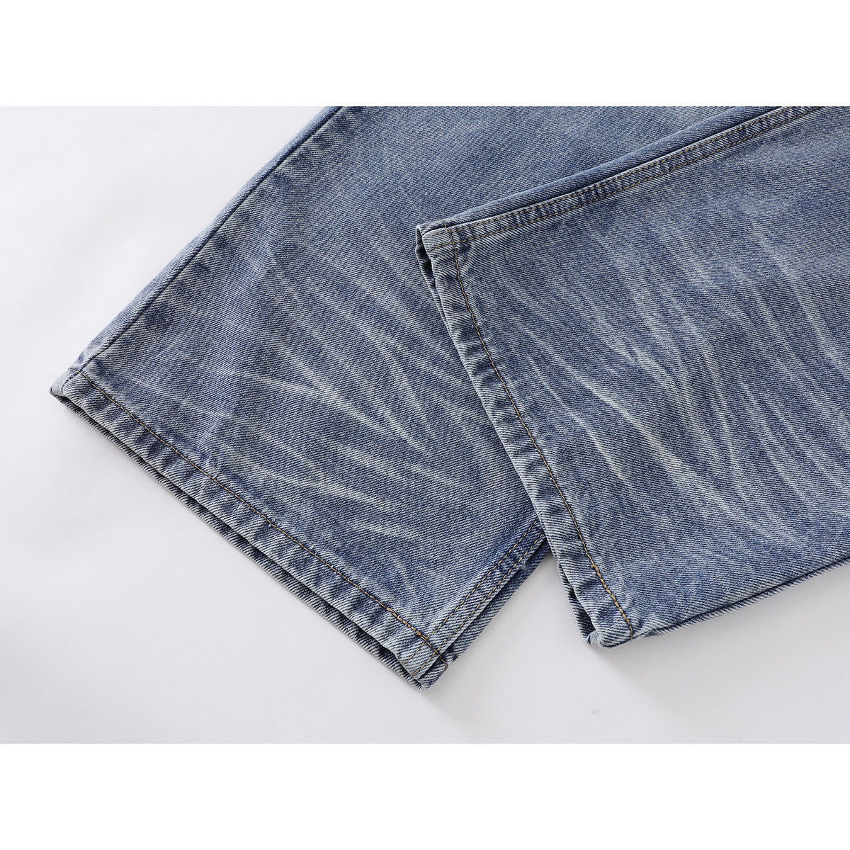 Close-up of the wide, faded blue denim jeans hems and leg seams.