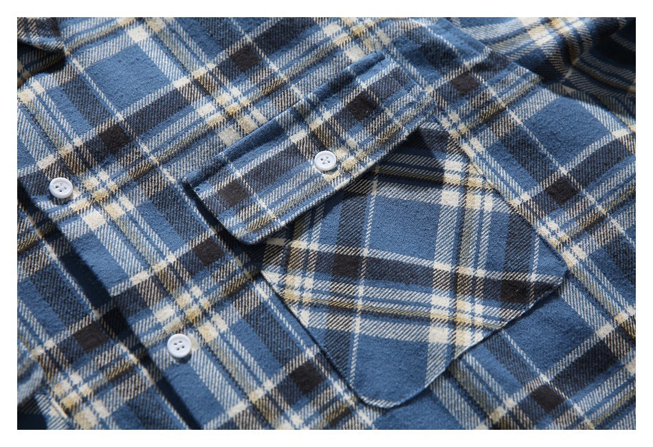Close-up of a blue plaid shirt front with white buttons and a flap pocket.