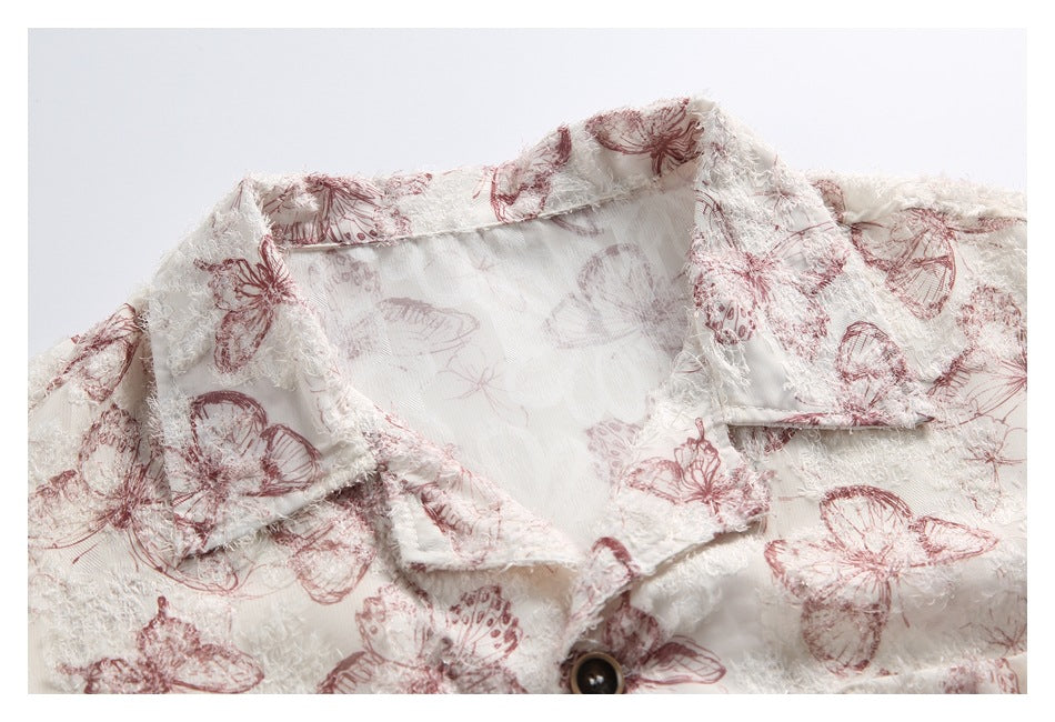 Close-up of the pointed collar and upper front of an ivory shirt with dusty rose butterfly print.