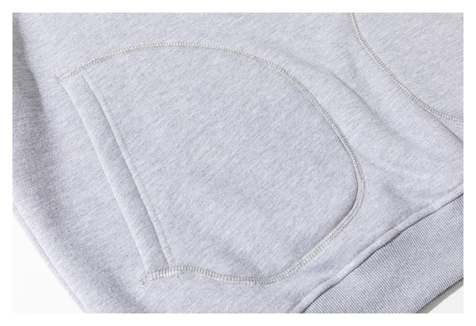 Close-up of curved stitching and a ribbed hem on a light gray sweatshirt.