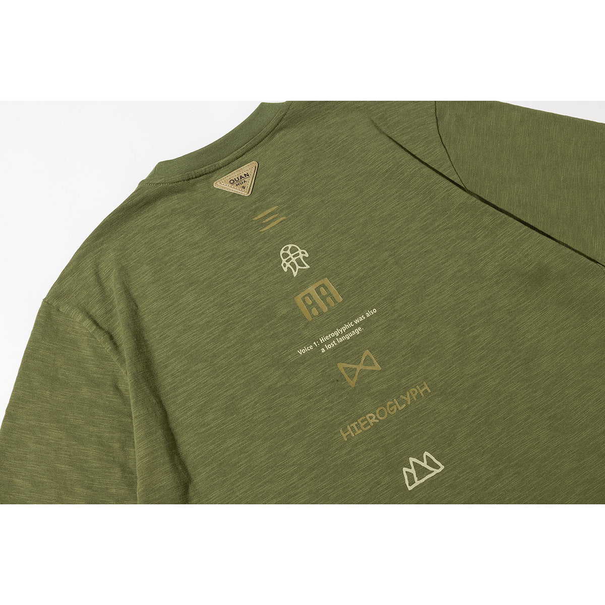 Close-up of the olive green T-shirt back with small printed symbols and text down the center.