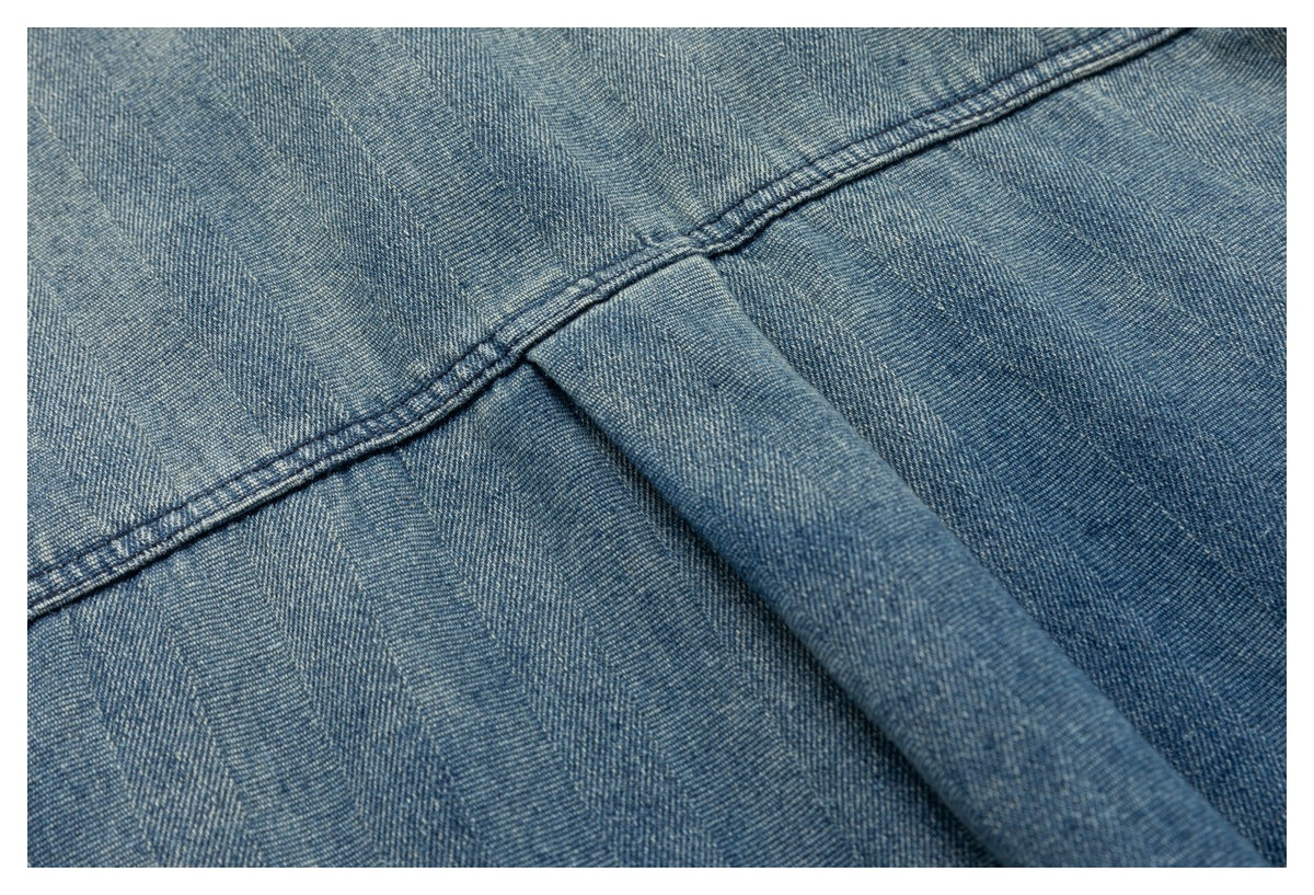 Close-up of blue denim fabric with a folded seam and visible double stitching.