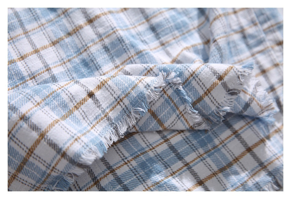 Close-up of pale blue plaid fabric with a frayed edge and loose threads.