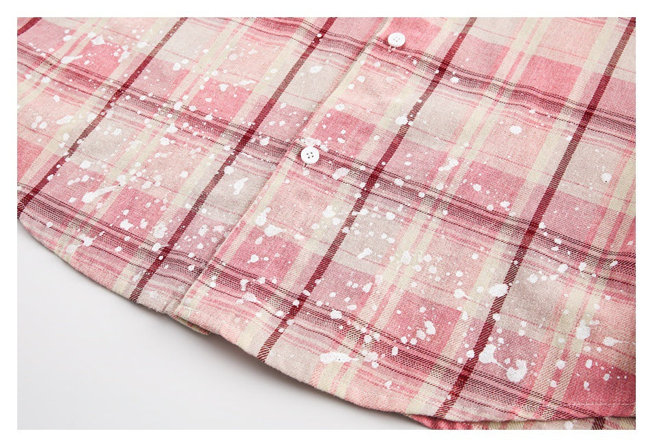 Close-up of the curved hem of a pink plaid shirt with white splatter marks.