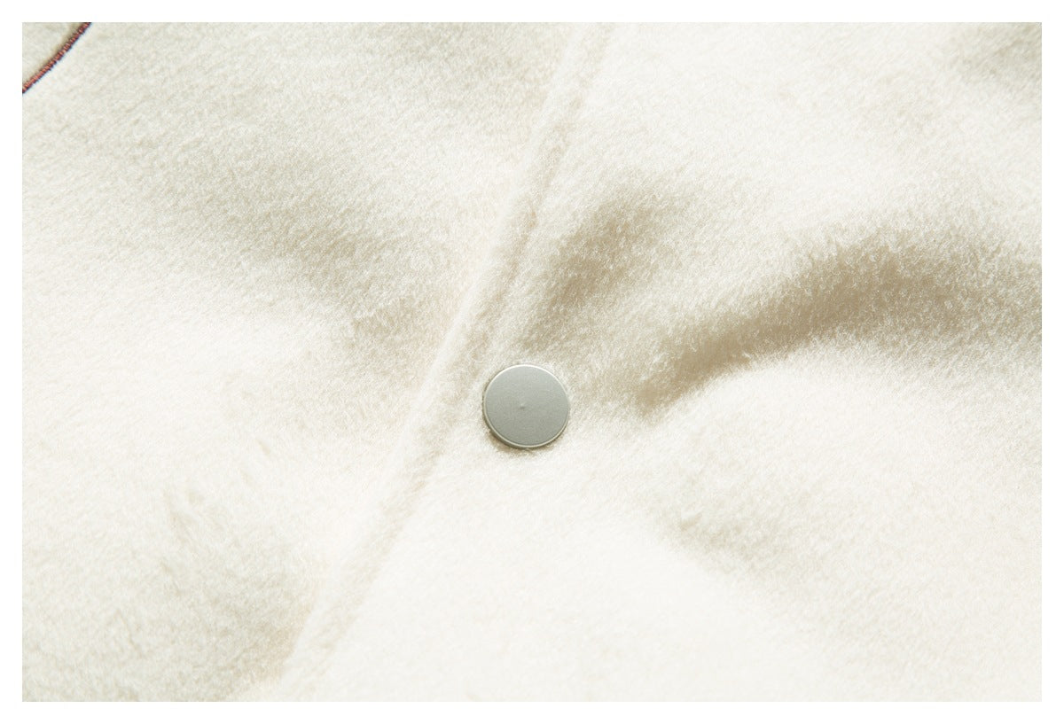 Close-up of a silver snap fastener on cream fabric with a glimpse of contrasting seam piping.
