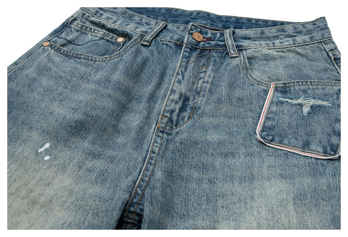 Close-up of the front of faded blue jeans with a button closure, front pockets, and distressed coin pocket.