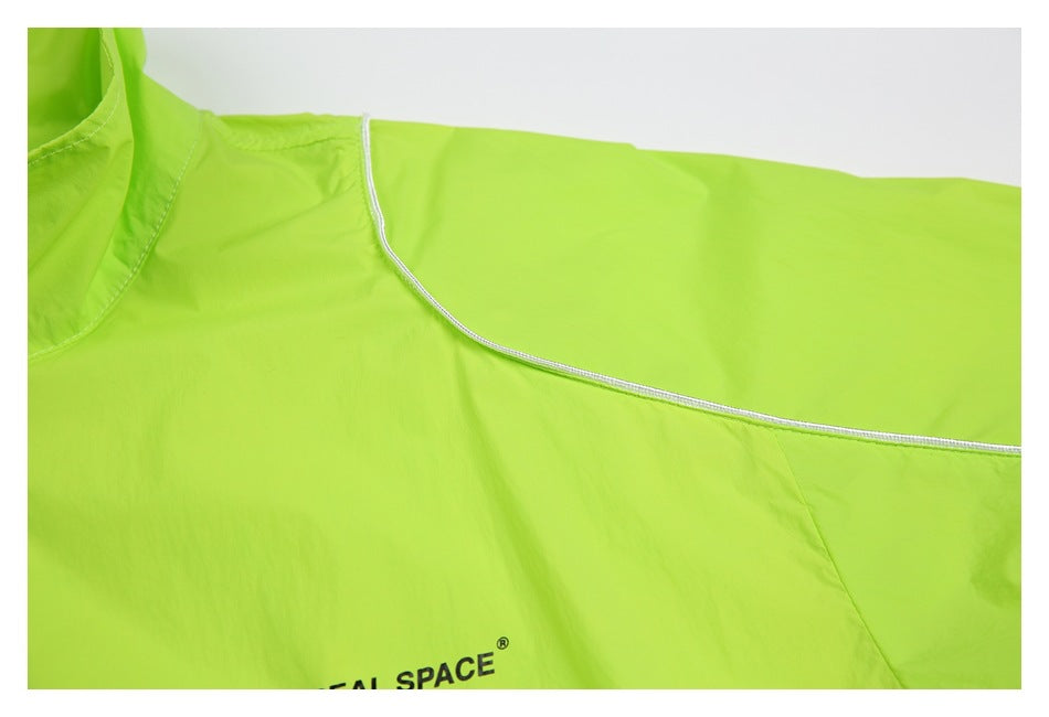 Close-up of a neon lime garment with white piping and partially visible black REAL SPACE lettering.