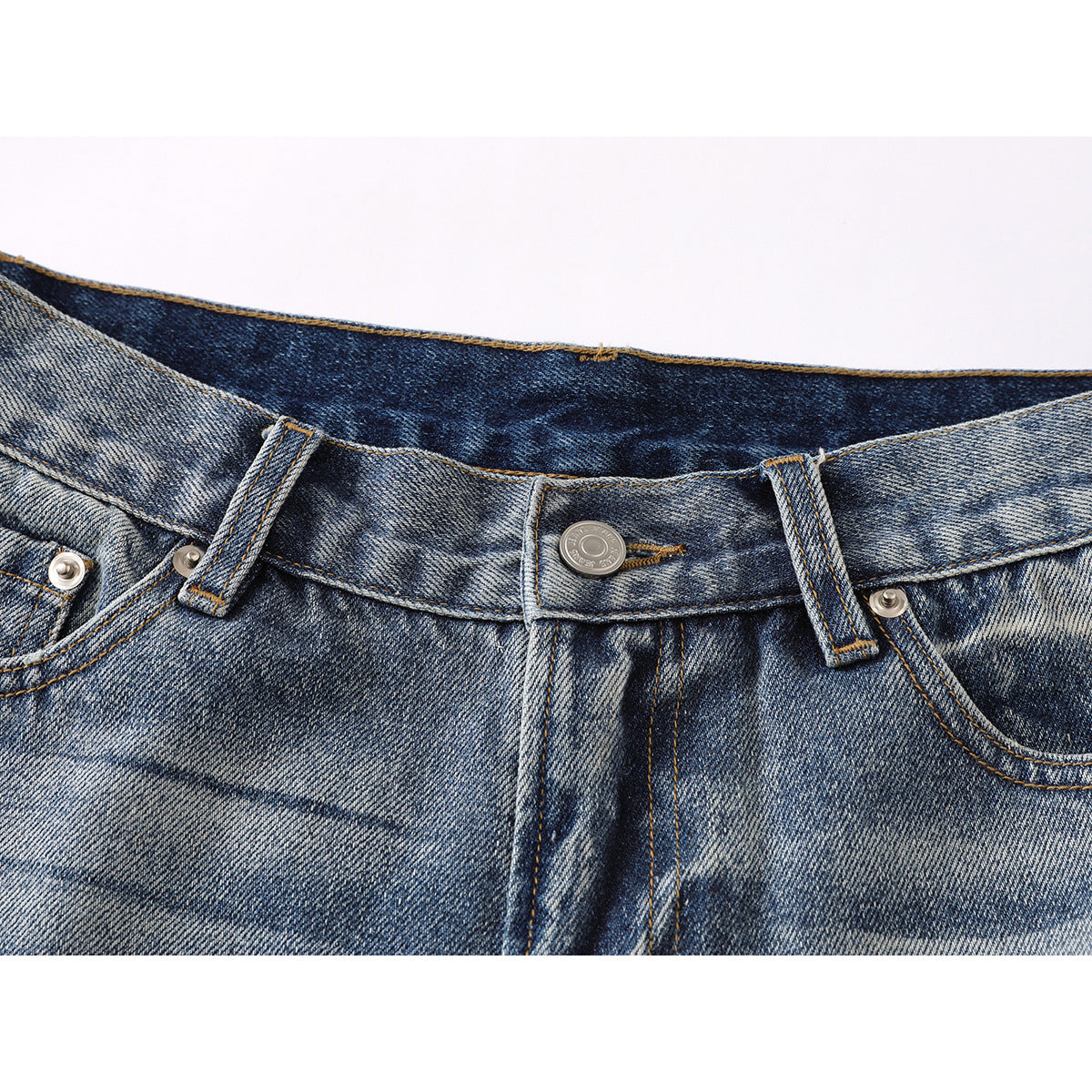 Close-up of the waistband, button, belt loops, and front pockets of blue washed jeans.