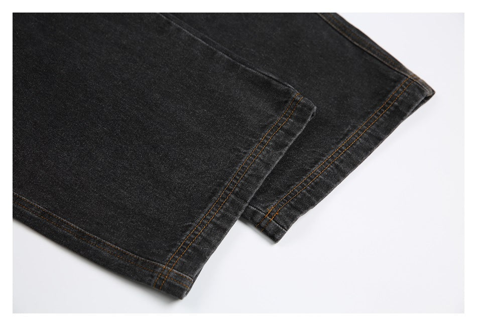 Close-up of the hems of black jeans with brown contrast stitching.