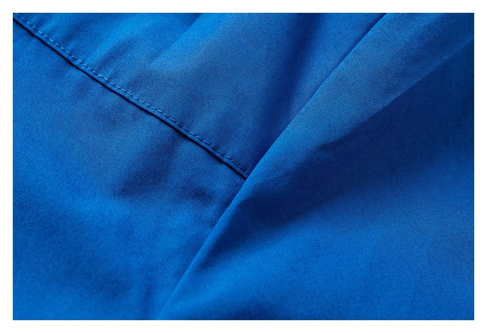 Close-up of bright blue fabric with a diagonal stitched seam and overlapping fold.