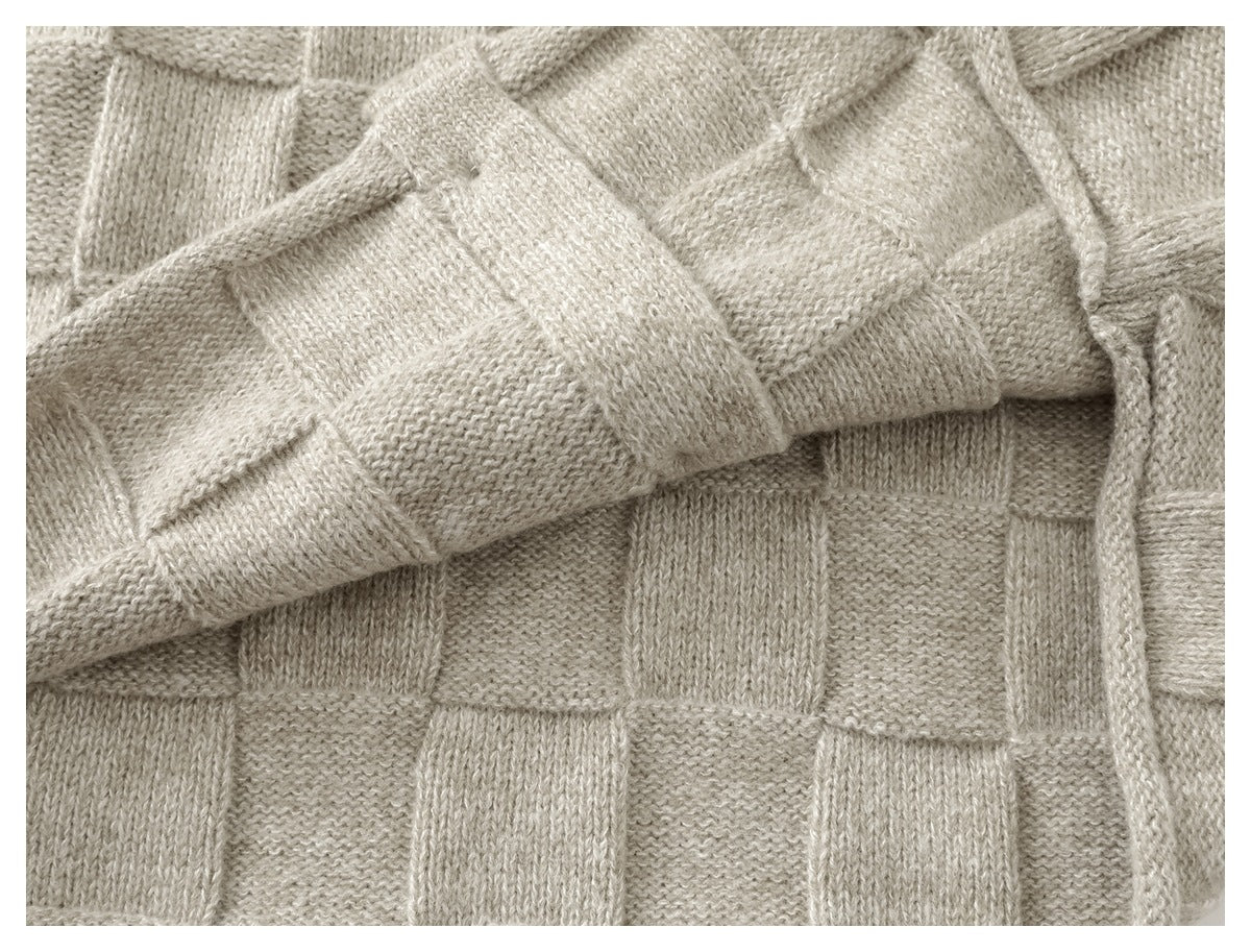 Close-up of the light beige cardigan’s sleeve and checkerboard knit pattern.