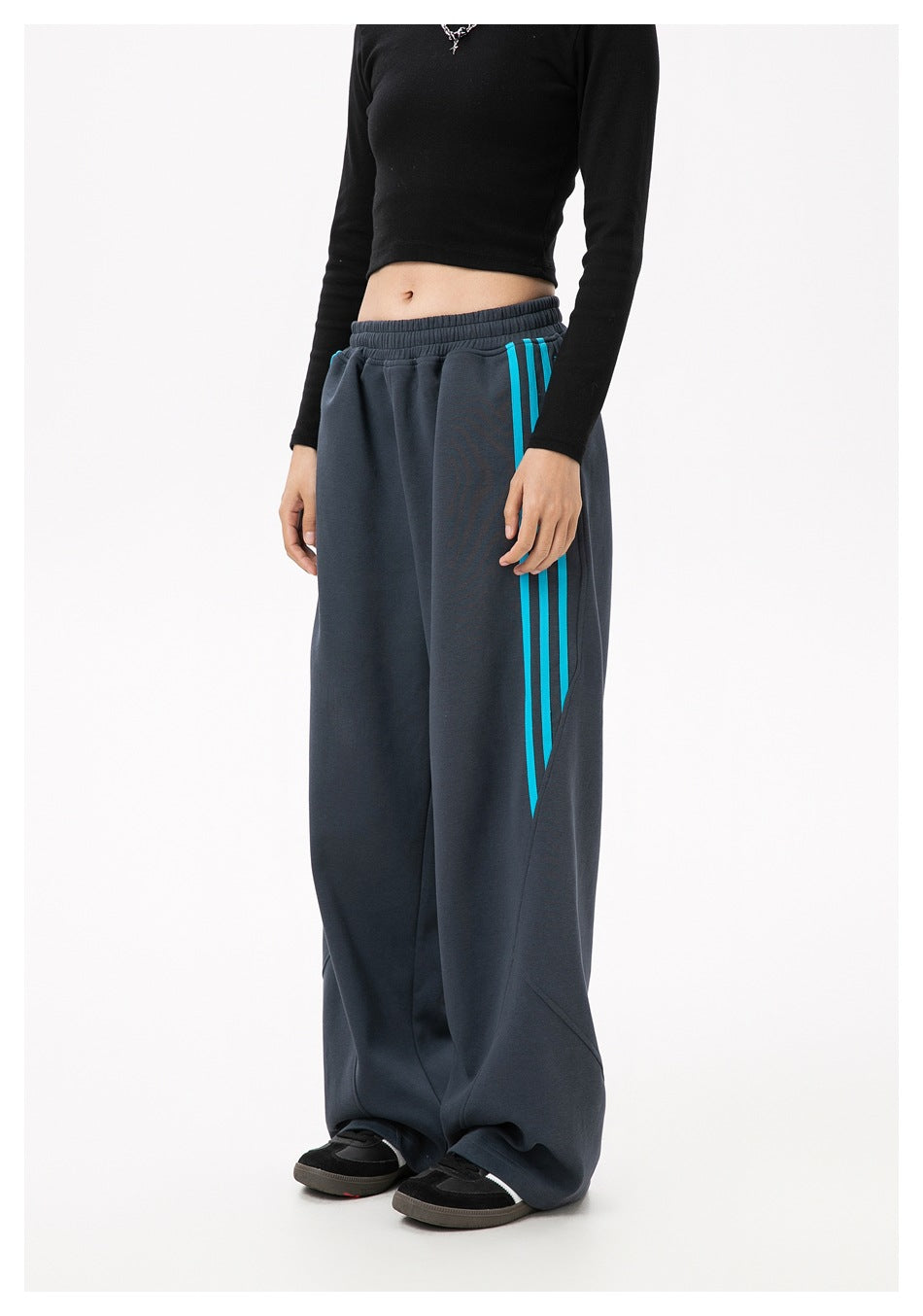 Cropped model view of charcoal wide-leg pants with turquoise side stripes and an elastic waistband.