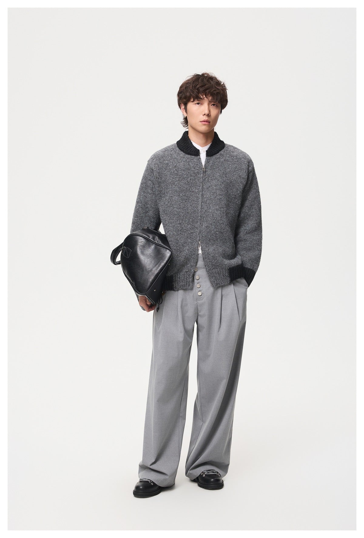 Model wearing a gray cardigan with black ribbed collar, cuffs and hem, styled with gray trousers.