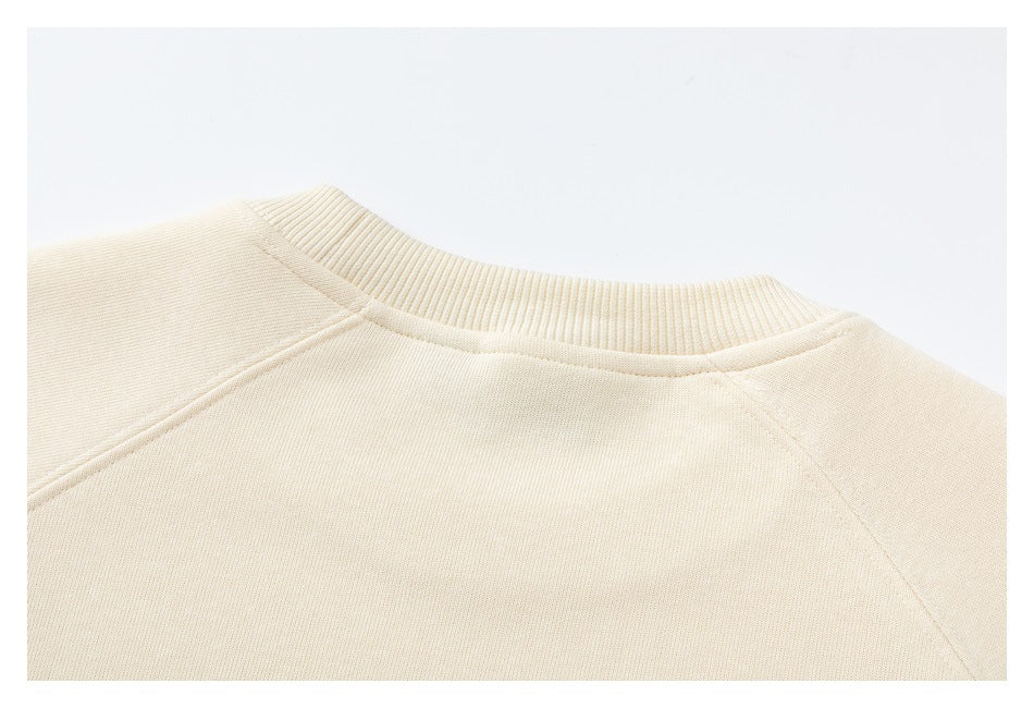 Close-up of the back neckline and shoulder seams of a cream sweatshirt.
