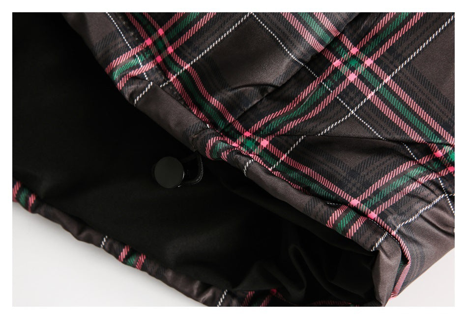 Close-up of a dark plaid garment opening with black lining and a round black snap fastener.