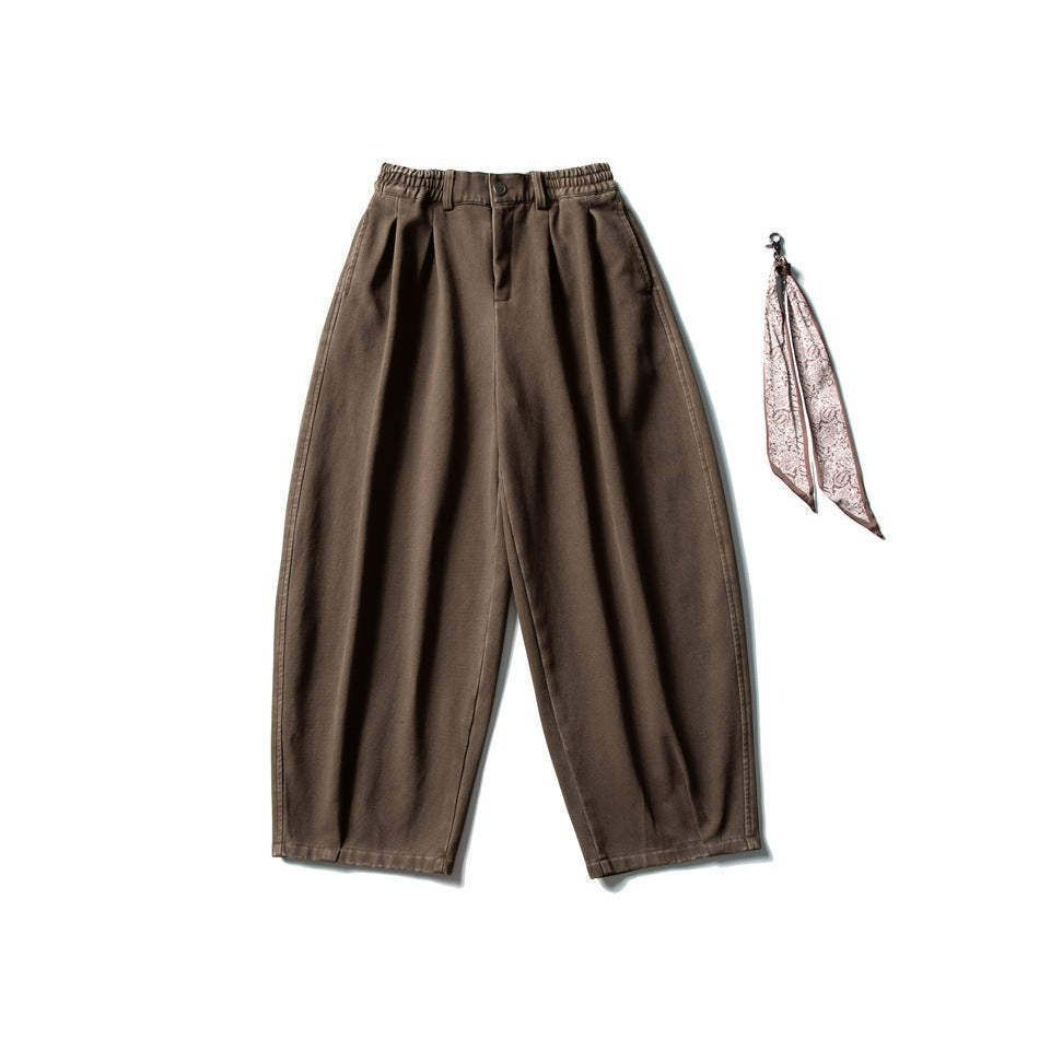 Front view of relaxed brown trousers with an elastic waist; a pink paisley scarf accessory is shown beside them.