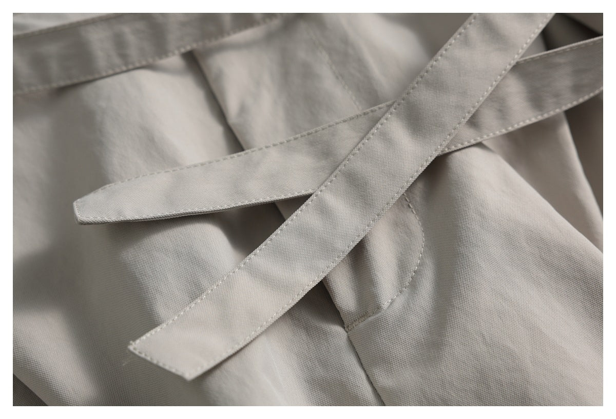 Close-up of overlapping light taupe fabric ties crossing over the garment.