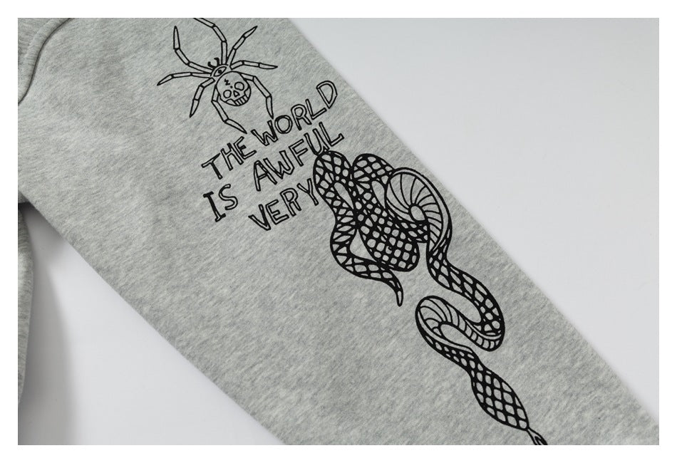 Close-up of a gray hoodie sleeve with a black spider, snake, and English lettering graphic.