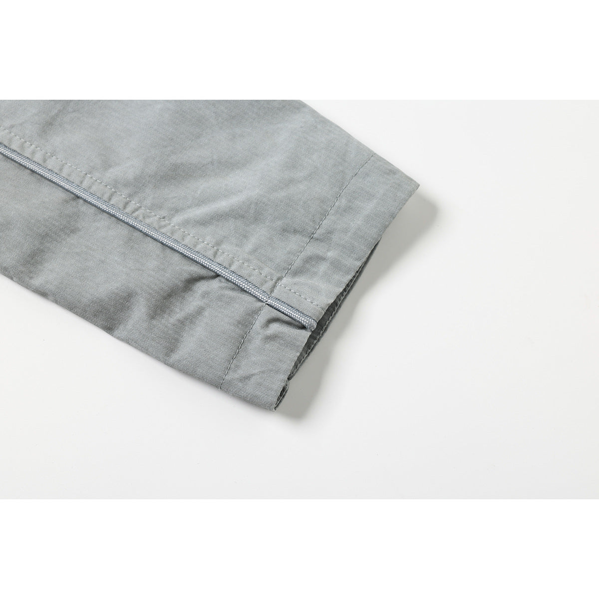 Close-up of the light gray jacket sleeve cuff and decorative bound seam.