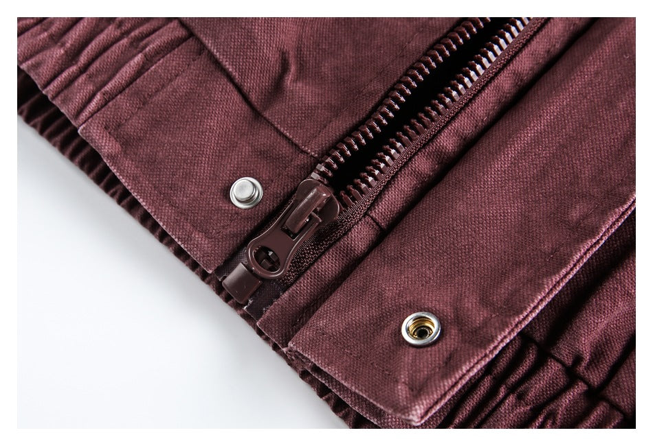 Close-up of a burgundy zipper with a large pull and metal eyelets along the edge.