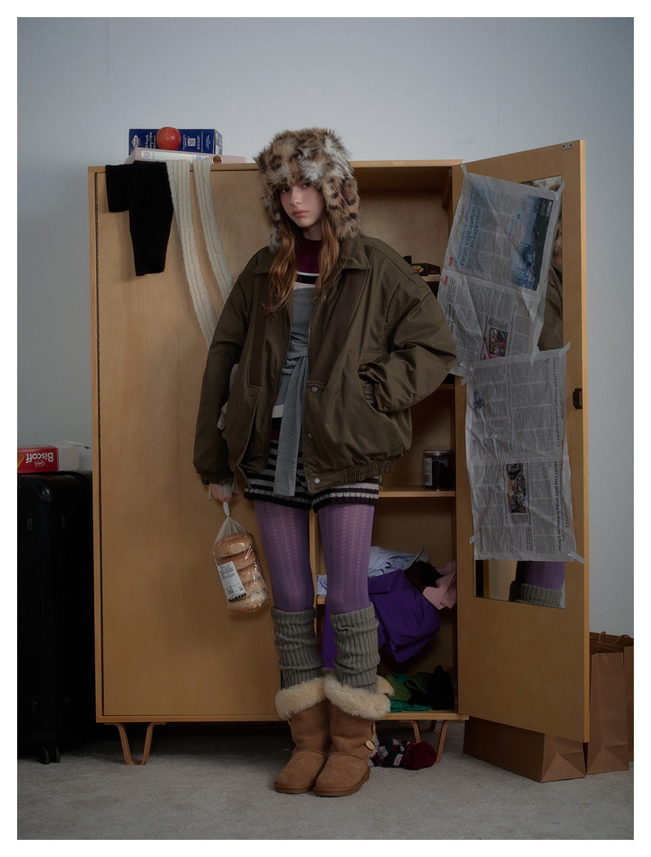 Full-length model wearing an oversized olive jacket, spotted fur hat, purple tights, gray leg warmers and brown boots.