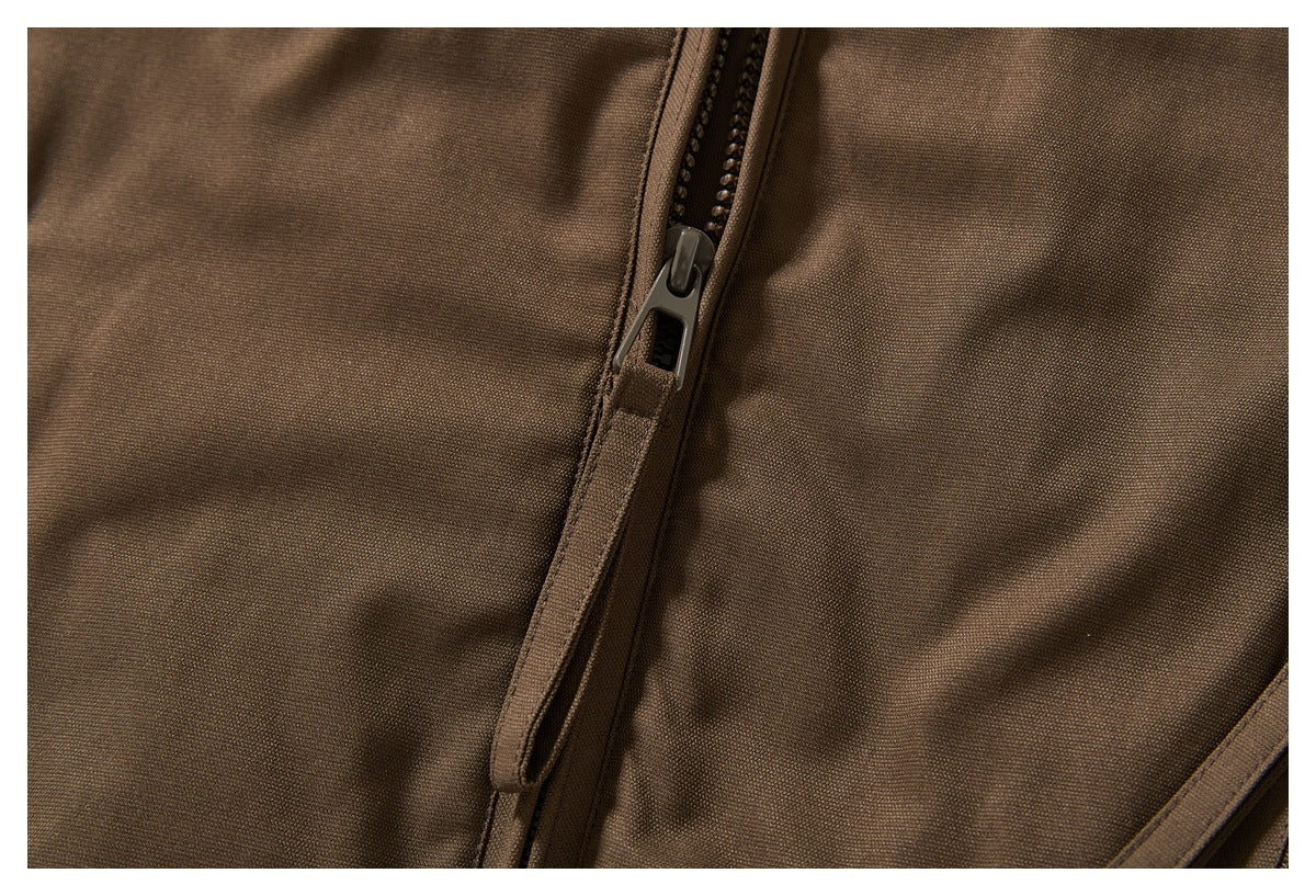Close-up of a dark zipper and pull on brown garment fabric.