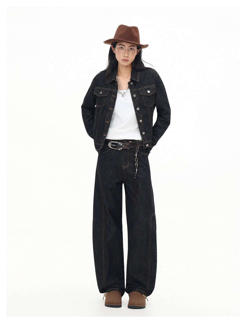 Full-length front view of a model wearing a black denim jacket and loose, wide-leg jeans.